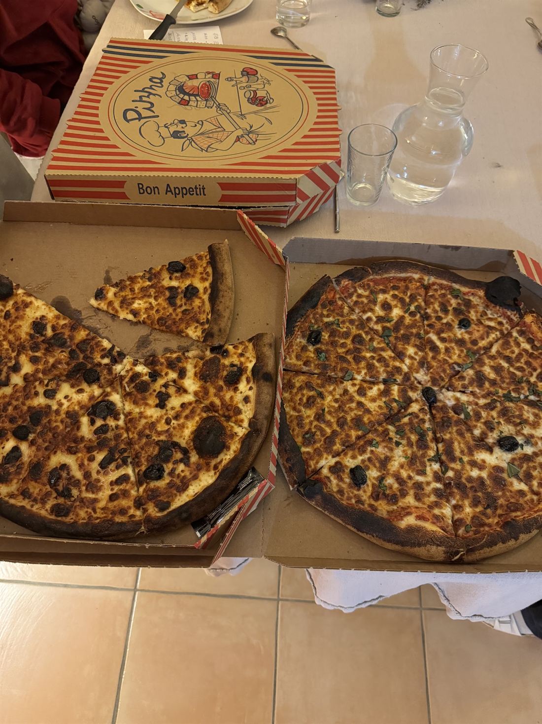 Deux pizzas dans leurs boîtes posées sur une table