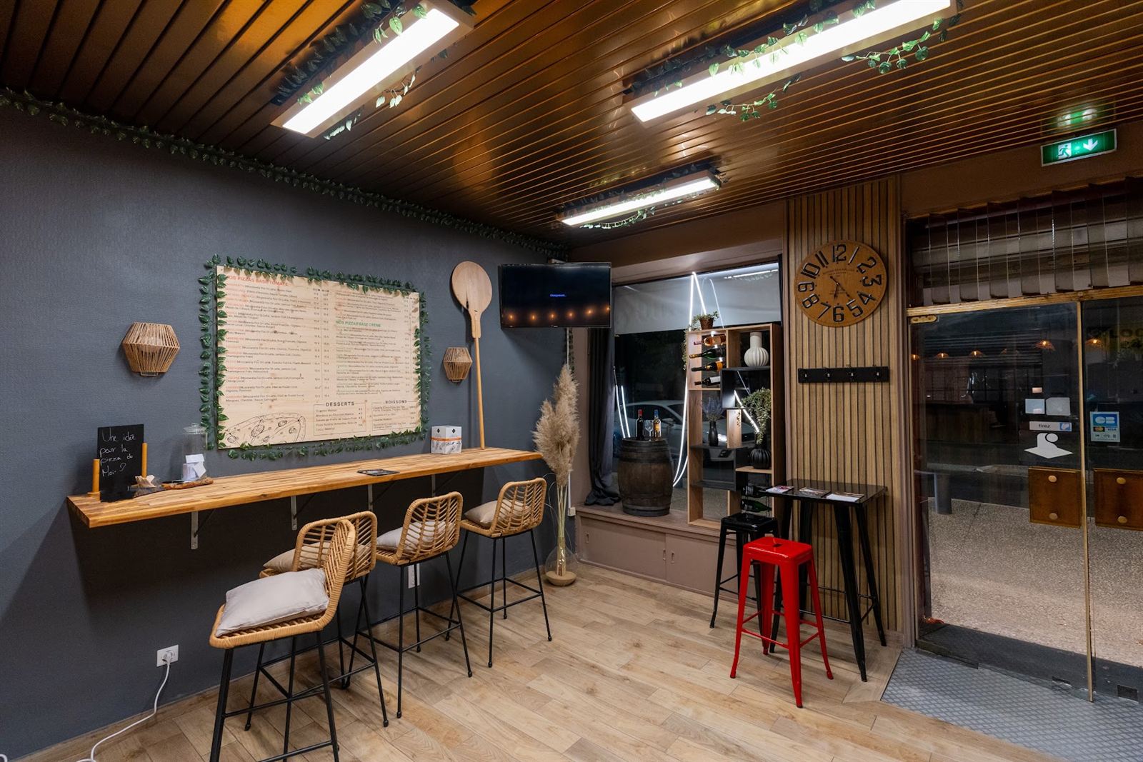 L’intérieur de la pizzeria : comptoir en bois et tabourets