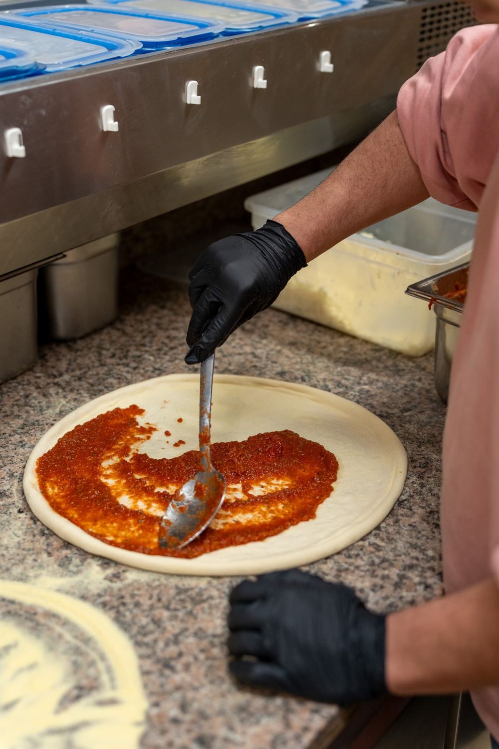 Le pizzaïolo étale la sauce tomate sur un disque de pâte