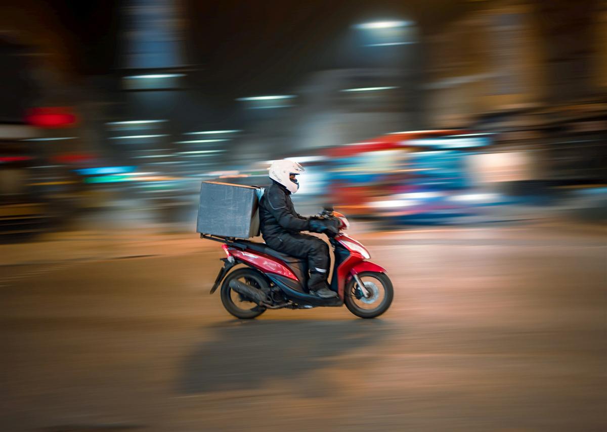 Un livreur à scooter filant dans la nuit (photo d’illustration)